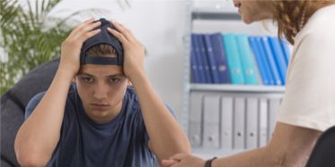 Young man in a backwards ballcap dealing with issues in therapy session