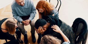 Young man getting support from others during a group therapy session