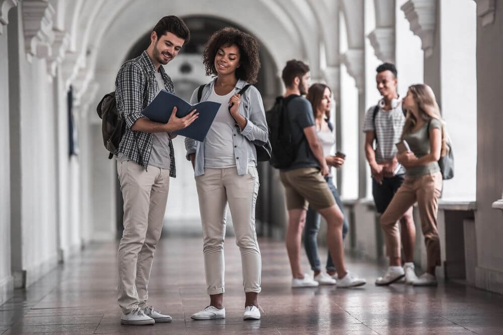 Florida Students Comparing Notes In Hallway For Their Online Psychology Doctorate Degree