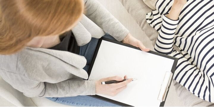 Psychologist working with reclined patient on a couch during therapy session