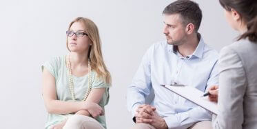 Wife ignoring her husband while struggling couple attends marriage therapy