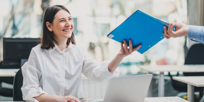 Woman handing colleague a binder