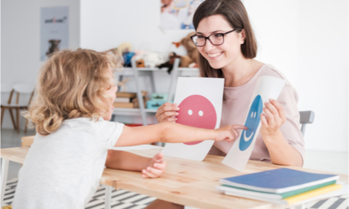 Young child pointing at a picture of a smiley face