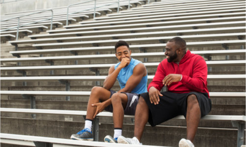 Two men laughing while sitting on stadium bleachers