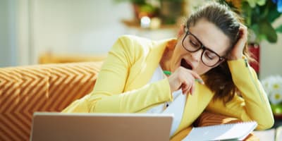 Student yawning with homework on the couch